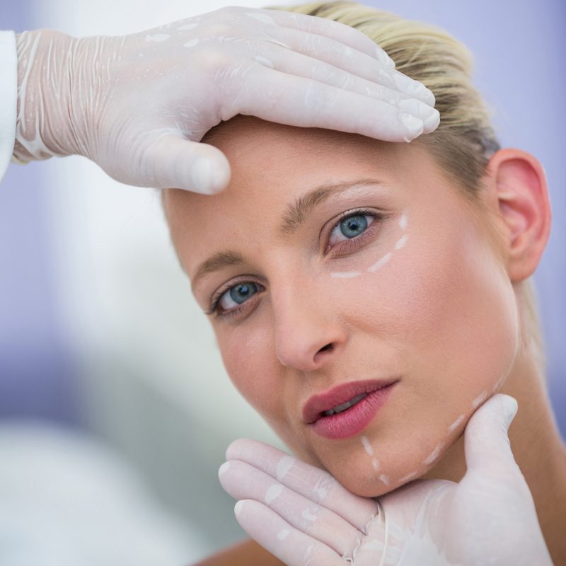 Close-up of doctor examining female patients face for cosmetic treatment